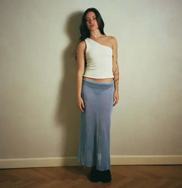 Front, full-length: white one-shoulder rib top, long sheer pale-blue knit skirt to the floor, black platform shoes.