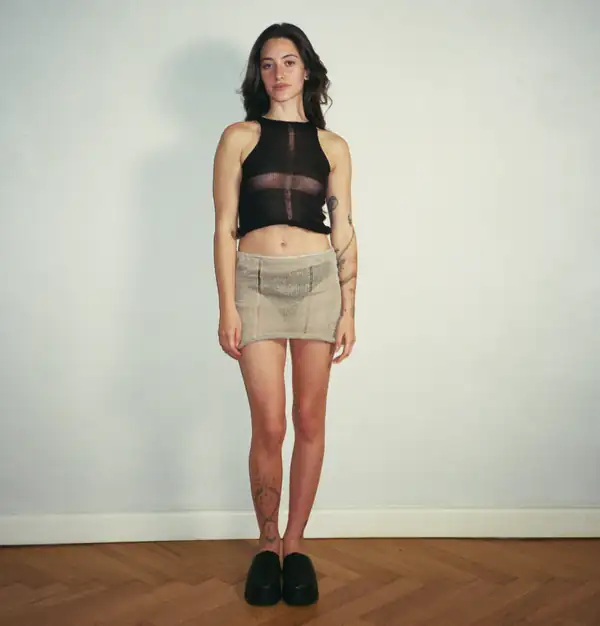 Front, full-length: black sheer knit halter and short oat knit mini skirt, black loafers.