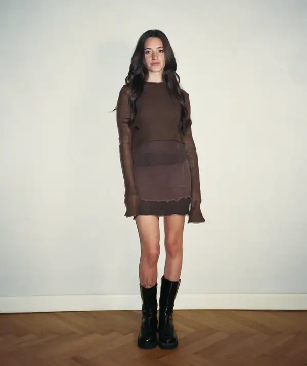 Front, full-length: brown sheer long-sleeve over the brown skirt, black boots.
