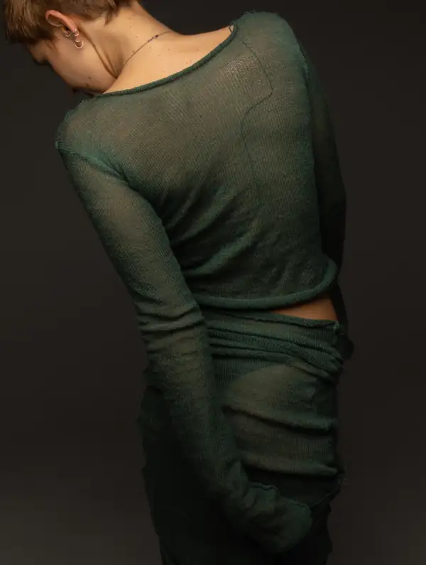 Back: the dark green sheer long-sleeve, skirt bunched at the hip.