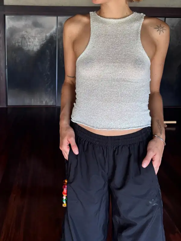 Front: pale grey ribbed knit halter tank, navy track pants, painted screens behind.