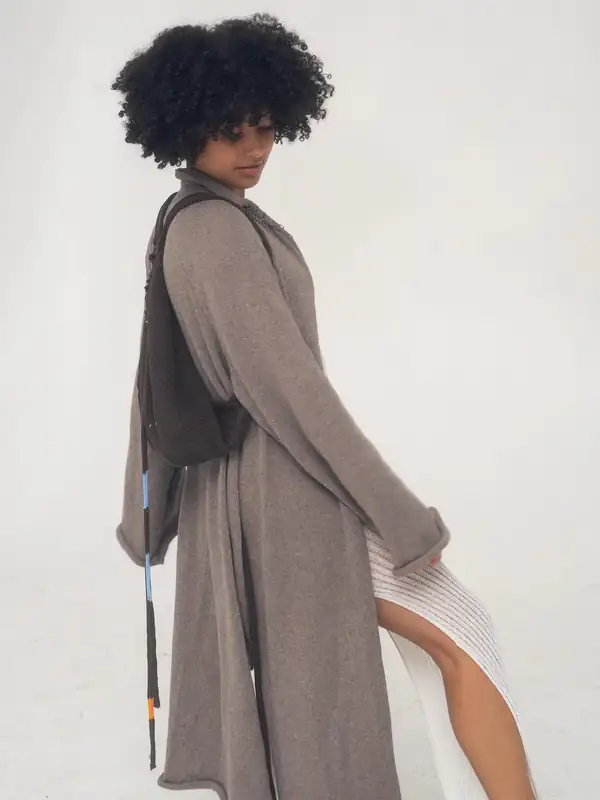Side, walking: the taupe coat over the white dress.