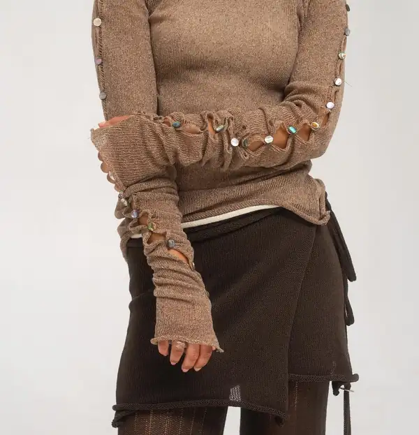 Close: hand and arm in the extra-long tan sleeve with a row of small buttons.