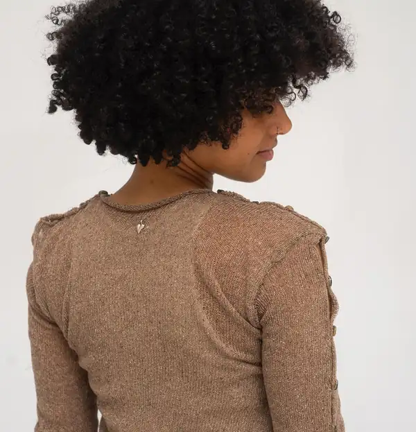 Back close: the tan top's shoulder seam and sleeve buttons.