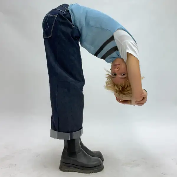 Folded double from the waist: pale blue knit tank with dark chevron stripes over a white tee, turned-up jeans, black boots.