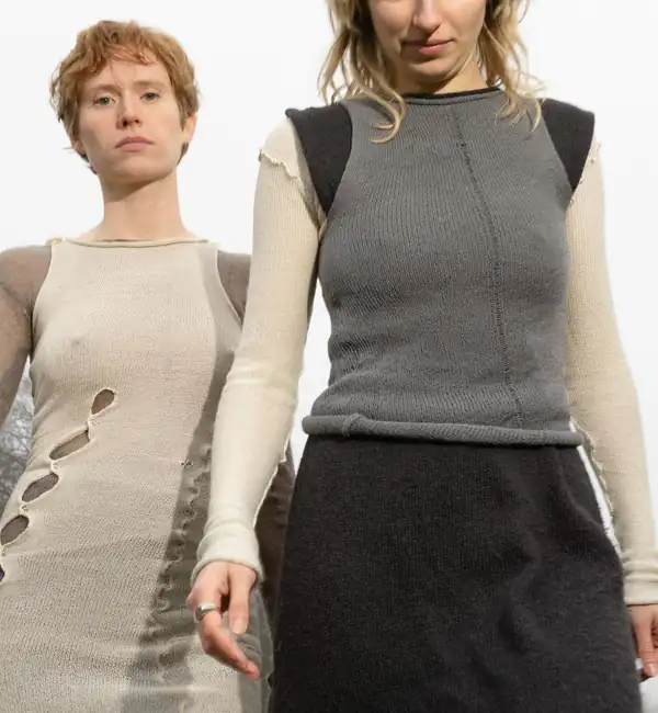 Two models, torso down: a cream ribbed long dress with cut-out detail, and a grey knit dress with contrast sleeves.