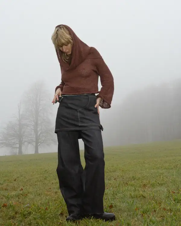 Full-length in fog: rust/brick knit hooded top over a black denim skirt and dark jeans.