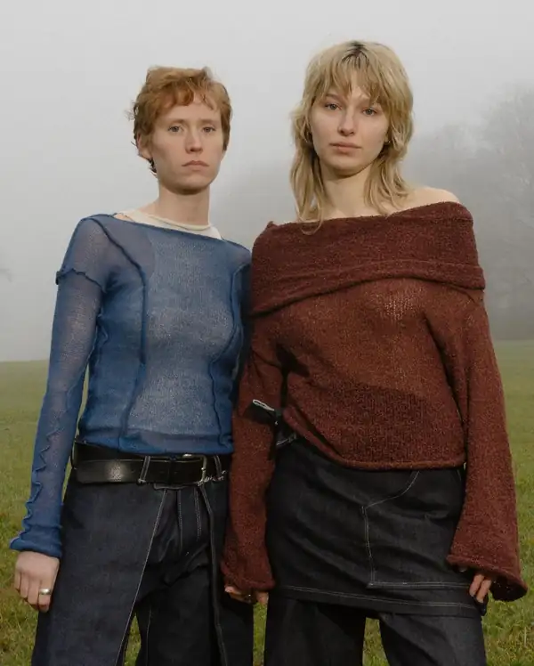 Two models in fog: one in a blue sheer knit long-sleeve, one in the rust off-shoulder knit.