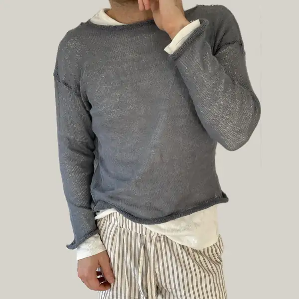 A man in a grey sheer knit crew jumper over a cream long-sleeve, striped trousers.