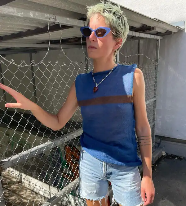 Same top, arm resting on the fence.
