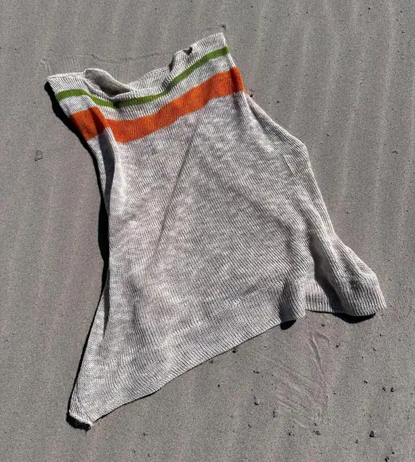 Flat lay on wet sand: the vest laid out showing its full pointed shape.