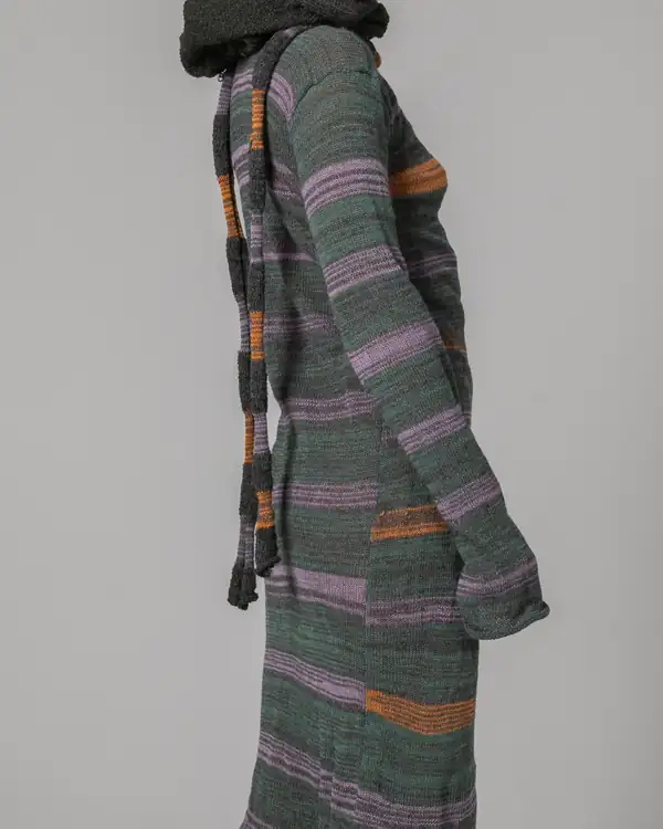 Profile with the hood up: the striped knit long coat with hanging ties.