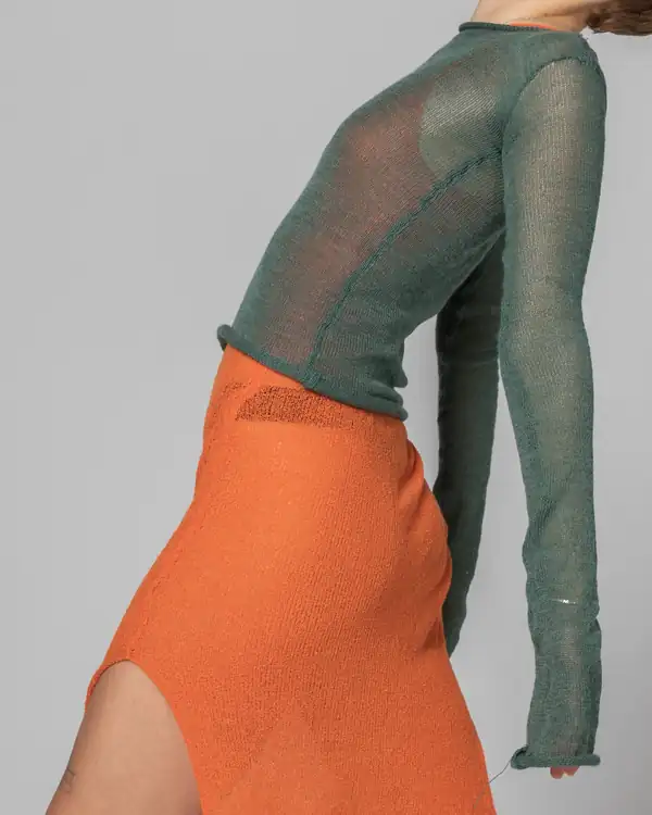 Bending: sage-green sheer knit long-sleeve over an orange knit skirt with a slit.