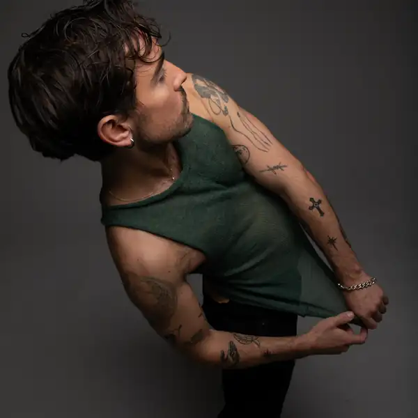 Bending sideways: the sage knit tank, tattooed arms.