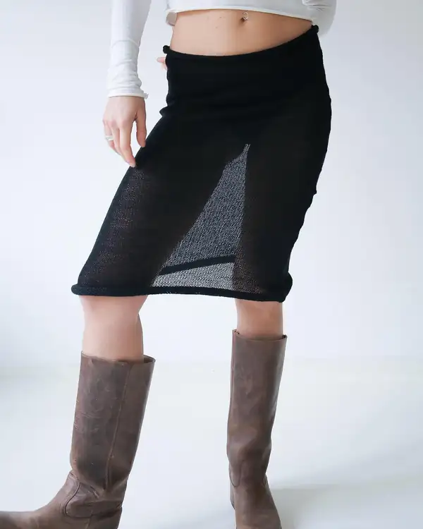 Front: black sheer knit pencil skirt with a rolled hem over brown leather knee boots, white long-sleeve above.