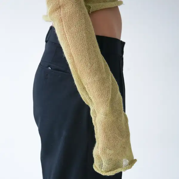 Close: one chartreuse sleeve hanging past the hip against black trousers.