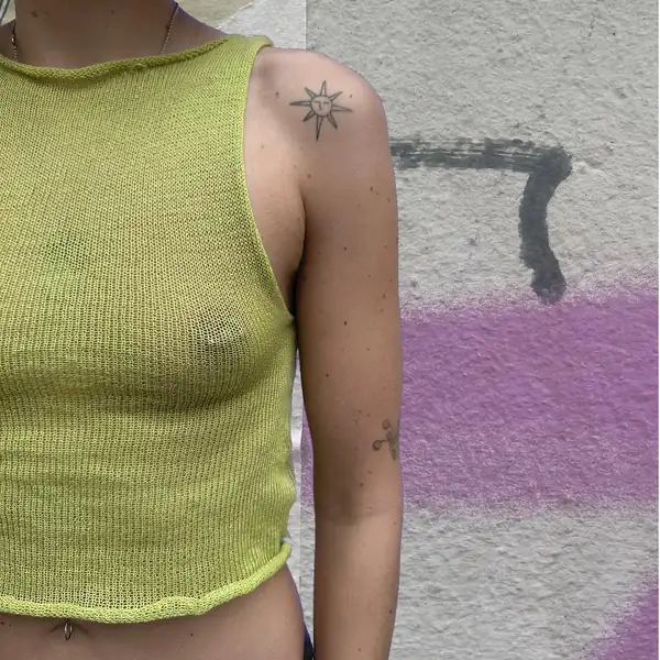 Side: chartreuse knit sleeveless top with a rolled hem.